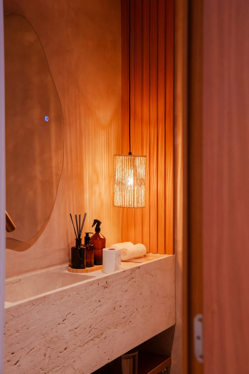 Stylish bathroom with stone sink, wooden wall, and hanging light