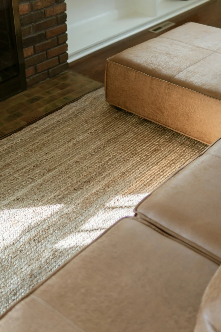 Tan leather sectional sofa and ottoman on rug