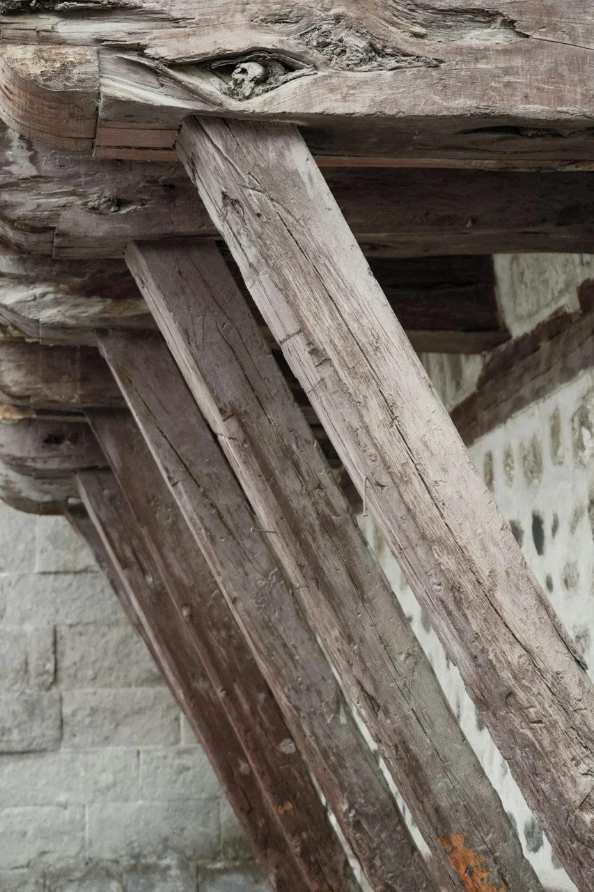 Weathered wooden support beams angled against a stone wall of a rustic building