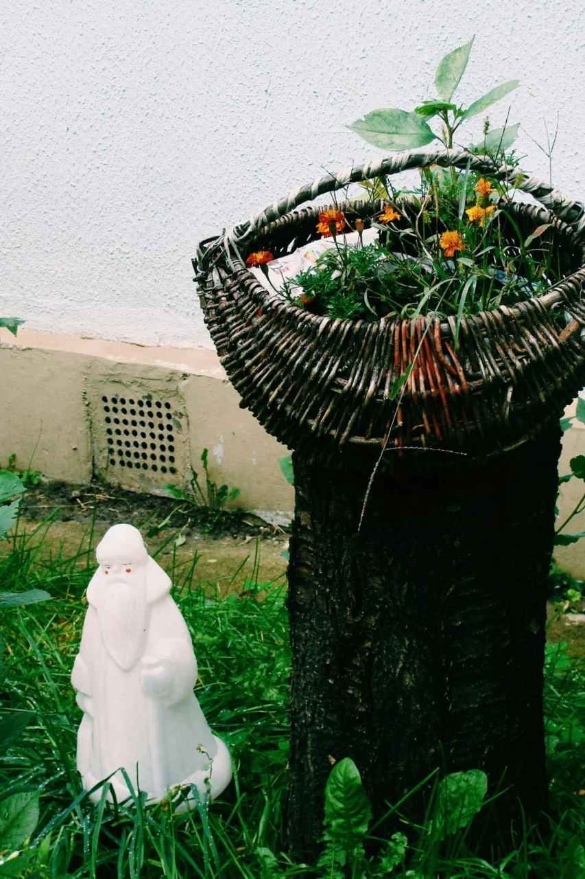 White gnome statue beside a rustic plant stand