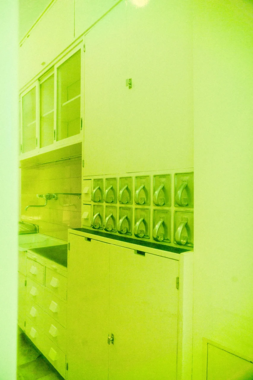White kitchen cabinets and sink bathed in yellow-green light