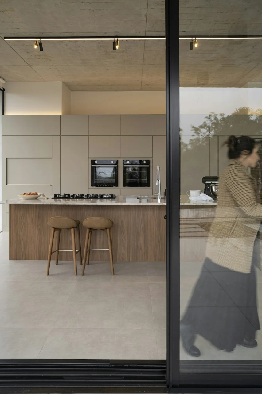 Woman walking past modern kitchen with island